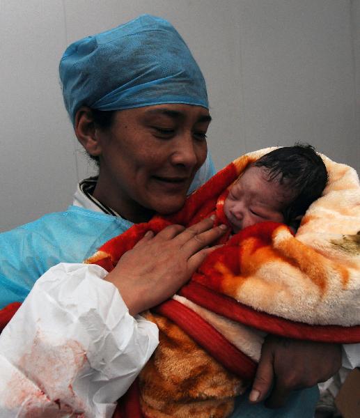 A charge nurse holds a newborn baby at a makeshift shelter in Yushu County, northwest China's Qinghai Province, on April 19, 2010.
