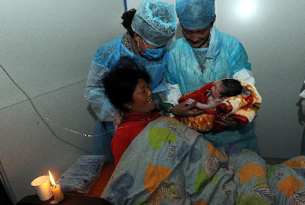Nurses bring a newborn baby before his mother at a makeshift shelter in Yushu County, northwest China's Qinghai Province, on April 19, 2010. 