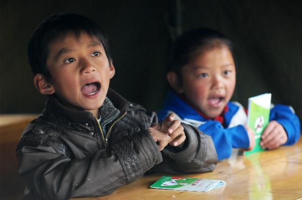 Children read books in a camp school in quake-hit Yushu County, northwest China&apos;s Qinghai Province, April 20, 2010. Volunteers from Mianyang City of Sichuan Province began to give classes in this camp school on Tuesday. [Xinhua]