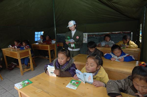A volunteer leads children to read books in a camp school in quake-hit Yushu County, northwest China&apos;s Qinghai Province, April 20, 2010. Volunteers from Mianyang City of Sichuan Province began to give classes in this camp school on Tuesday.[Xinhua]