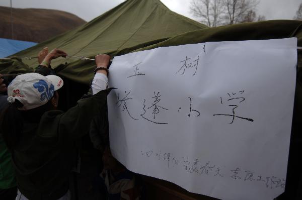  A volunteer hangs a paper with school&apos;s name in a camp school in quake-hit Yushu County, northwest China&apos;s Qinghai Province, April 20, 2010. Volunteers from Mianyang City of Sichuan Province began to give classes in this camp school on Tuesday. [Xinhua]