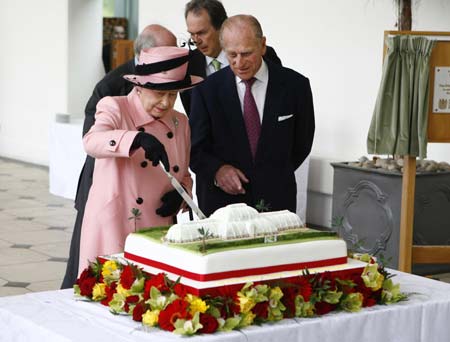 Britain&apos;s Queen Elizabeth cuts a cake as Prince Philip watches during their visit to the Royal Botanic Gardens for its 250th anniversary at Kew, London, May 5, 2009.