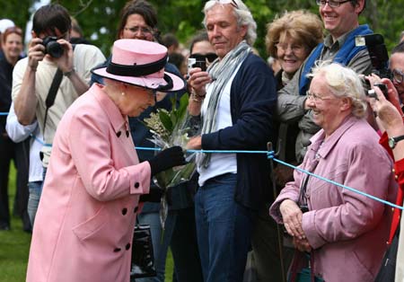 Britain&apos;s Queen Elizabeth smells a bouquet of flowers given to her during a visit to the Royal Botanic Gardens for its 250th anniversary at Kew, London, May 5, 2009.