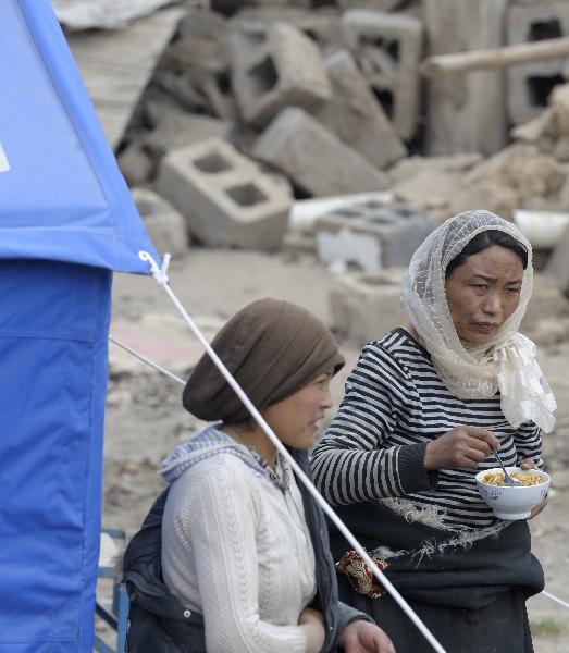 Local residents stand in front makeshift tents at the quake-devastated Zhaxi Datong Village, in Gyegu Town, Yushu County, northwest China's Qinghai Province, April 19, 2010. Zhaxi Datong Village is the worst-hit area during the April 14 quake in Qinghai. It has been mostly razed to the ground and 120 of the total about 670 villagers here lost their lives.