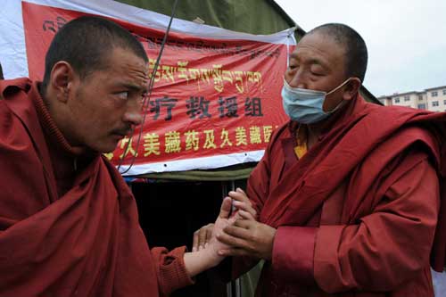 A Tibetan doctor (R) examines injuries for a Lama at a temporary shelter in Yushu prefecture of Qinghai province, April 20, 2010.