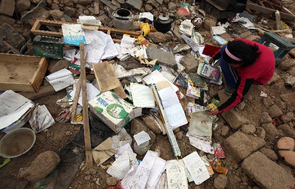 A girl is looking for her school textbooks in the heaps of debris of her collapsed house on April 21, 2010. It has been more than a week since a devastating earthquake hit Yushu, northwestern China's Qinghai province on April 14, 2010. 