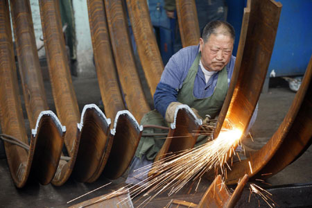 A worker cuts steel bars at a mill in Huaibei, Anhui province. [China Daily]