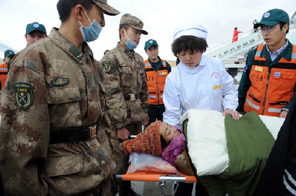 Rescuers carry an injured to an aircraft at an airport in quake-hit Yushu County, northwest China's Qinghai Province, April 22, 2010. The injured people were continually transported by aircraft from quake-hit Yushu County to Xining, capital of Qinghai, on Thursday. [Xinhua]