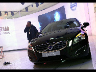 A staff member stands next to a Volvo S60 during its world premiere ceremony ahead of the Beijing Auto Show, in Beijing April 22, 2010. [Xinhua] 