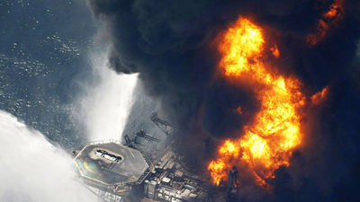 Burning oil rig sinks, oil slick spreads