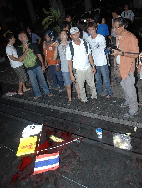 People look at the bloodstain after an explosion on Silom Road in the financial district of central Bangkok,capital of Thailand,April 22,2010.[Shi Xianzhen/Xinhua]