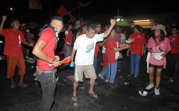 'Red-shirt'anti-government protesters gather after an explosion on Silom Road in the financial district of central Bangkok,capital of Thailand,April 22,2010 0.At least five people died and some 100 others were injured in a series of bomb blasts that hit Bangkok's main financial district of Silom on Thursday night,media sources said.[Shi Xianzhen/Xinhua]