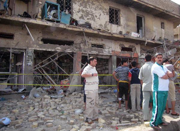 Iraqis stand in front of the collapsed building after a seris of deadly bombings on Friday in Baghdad. Reportedly at least 60 people were killed and 117 wounded in the bombings in Baghdad and western Anbar province. [Xinhua/AFP Photo]