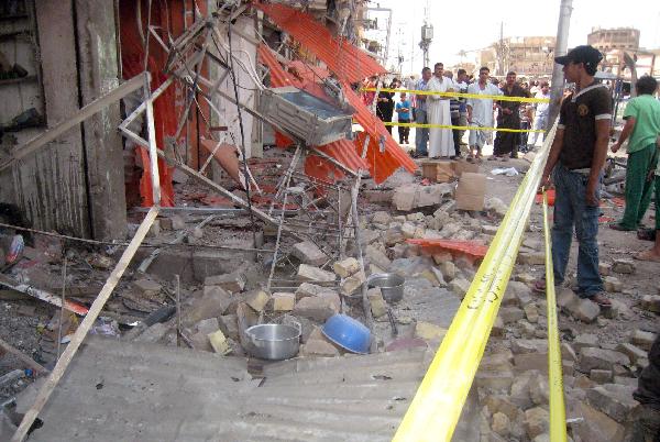 Iraqis stand in front of the collapsed building after a seris of deadly bombings on Friday in Baghdad. Reportedly at least 60 people were killed and 117 wounded in the bombings in Baghdad and western Anbar province. [Xinhua/AFP Photo]