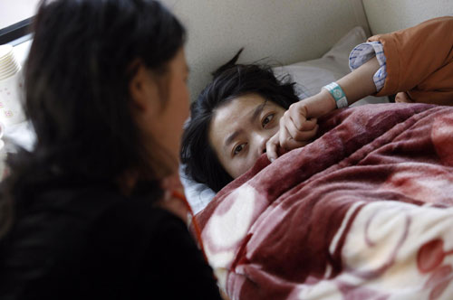 Accompanied by family members, an injured quake victim from Yushu lies in a carriage of a train bound for Xi'an to receive medical treatment, April 24, 2010. [Photo/Xinhua]