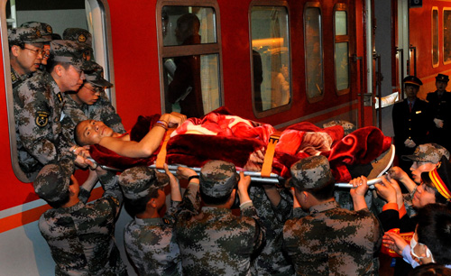 Rescuers take an injured man from the Yushu earthquake out of an express train in Xi'an, capital of Northwest China's Shaanxi province on April 24, 2010. [Photo/Xinhua] 