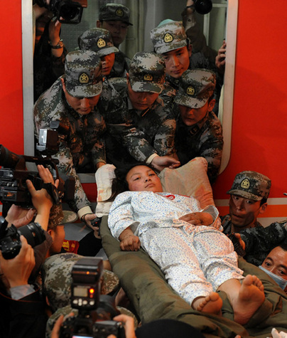 Rescuers take an injured woman from the Yushu earthquake out of an express train in Xi'an, capital of Northwest China's Shaanxi province on April 24, 2010. [Photo/Xinhua]