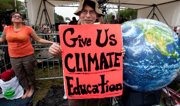 A man holds a cardboard written with Give Us Climate Education at a concert named Climate Rally at the National Mall in Washington D.C, capital of the United States, April 25, 2010. The Climate Rally was held Sunday to honor the Earth Day that falls on April 22 and call for fighting against climate change. [Zhu Wei/Xinhua]