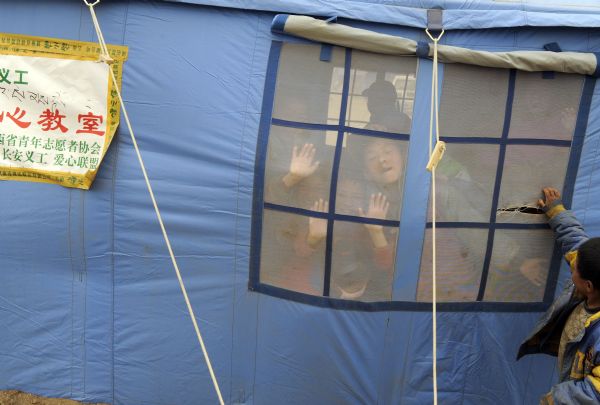 Children of Tibetan ethnic group play games during a short break among classes inside the temporary classroom at racecourse Gyegu Town of quake-hit Tibetan Autonomous Prefecture of Yushu, northwest China's Qinghai Province, April 25, 2010.