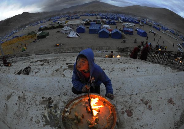 A boy of Tibetan ethnic group light lamps at a racecourse in quake-hit Tibetan Autonomous Prefecture of Yushu, northwest China's Qinghai Province, April 24, 2010. 