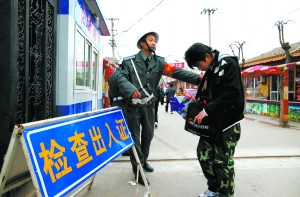 Resident shows ID card to get in the village. [Beijing News]