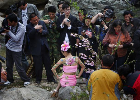 People take pictures of models with body painting at the scenic zone of Yangzigou in Luoyang, Henan Province, April 24, 2010. 