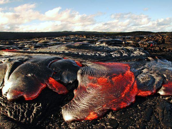 Pahoehoe Lava, Hawaii Pahoehoe lava flows on Kilauea Volcano in Hawaii Volcanoes National Park. Unlike aa (pronounced “ah ah‿ lava, pahoehoe flows relatively slowly, allowing an insulating skin to form that keeps the temperature close to 2,190 degrees Fahrenheit (about 1,200 degrees Celsius). Aa lava, on the other hand, moves faster and doesn’t have time to develop a skin, resulting in a cooler flow with a more angular texture.[Steve and Donna O’Meara/CNTV]