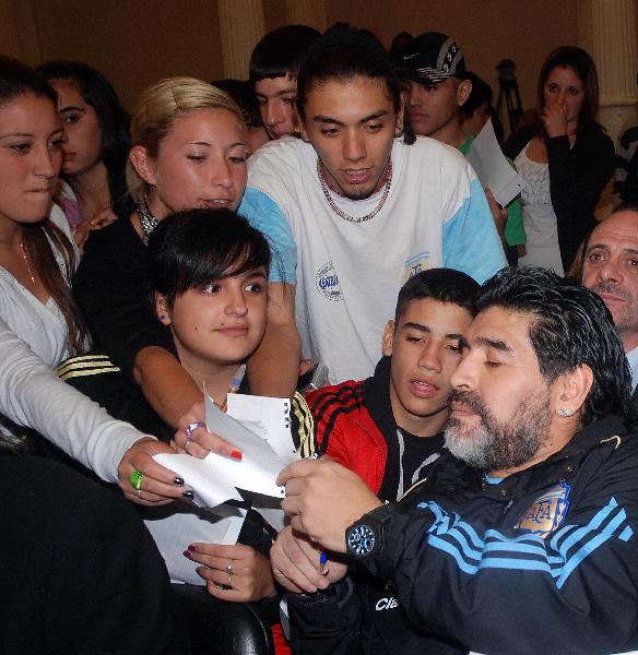 Argentina national team coach Diego Maradona (front R) signs autographs for fans while promoting 2010 South Africa World Cup themed books at the Buenos Aires International Book Fair 2010 in Buenos Aires, Argentina, on April 26, 2010. (Xinhua/Roberto Azcarate)