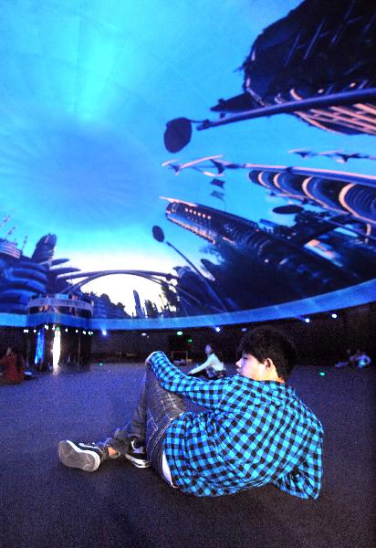 A visitor watches full dome film at the Pavilion of City Being during the trial operation in Shanghai Expo Park in Shanghai, east China, April 25, 2010. The Shanghai expo conducted trial operations for six times on April 20 - 26. [Xinhua/Wang Song]