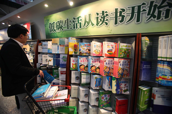 A man buys books in front of a low-carbon-themed bookshelf in Beijing Book Building in Beijing, China, April 27, 2010. A collection of books in the theme of low carbon and environment protection here is welcomed by the public recently. [Xinhua]