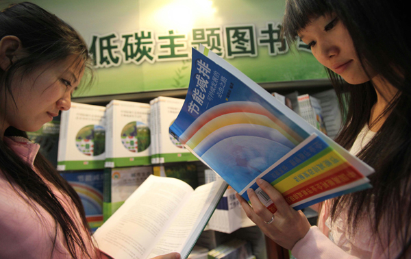 Two women read books in front of a low-carbon-themed bookshelf in Beijing Book Building in Beijing, China, April 27, 2010. [Xinhua]