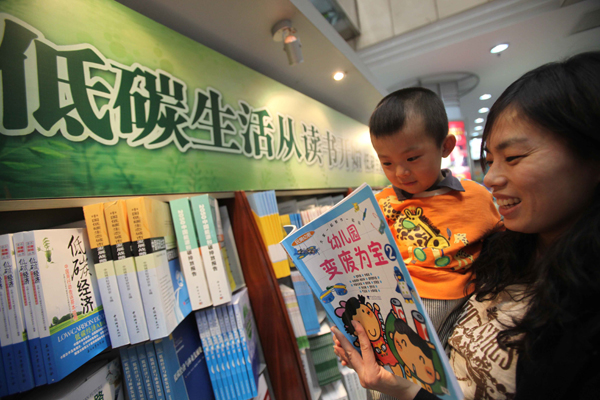 A mother shows a book to her child in front of a low-carbon-themed bookshelf in Beijing Book Building in Beijing, China, April 27, 2010.[Xinhua]