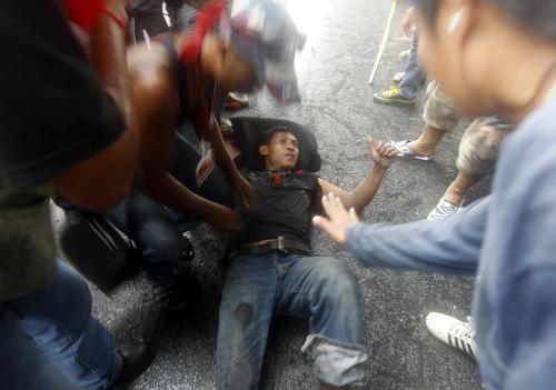 An anti-government &apos;red shirt&apos; protester receives first aid after being injured in clashes with Thai army soldiers near the old airport in the northern suburbs of Bangkok April 28, 2010. Thai troops fired live rounds in the air and shot rubber bullets in a chaotic clash with anti-government protesters on a highway in Bangkok&apos;s suburbs on Wednesday that wounded 10 people and possibly killed one. [Xinhua]