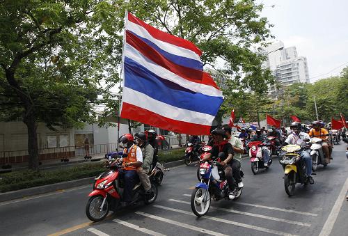 Anti-government &apos;red-shirt&apos; protesters carry Thai national flags and red flags as they ride motorcycles in a convoy on a main road on their way towards the northern suburbs of Bangkok April 28, 2010. [Xinhua]