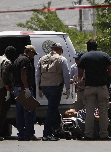 Policemen investigate a victim shot by an unknown armed men in in the northern Mexican city of Ciudad Juarez, April 28, 2010.[Xinhua] 