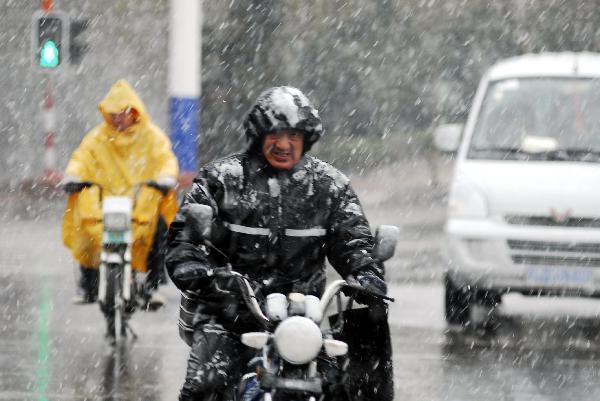 People on motorbike go against the snow on the road in Yantai, east China's Shandong Province, April 28, 2010. A snowfall hit the city on Wednesday.[Xinhua]