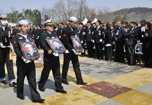 Choi Won-il, 2nd left, captain of the sunken South Korean naval ship Cheonan, and the survivors holding portraits of the victims pass by family members during a funeral ceremony at a navy base at Pyeongtaek, south of Seoul Thursday, April 29, 2010. South Korea honored 46 sailors Thursday with a tearful military funeral a month after a blast sank their warship. [Xinhua]