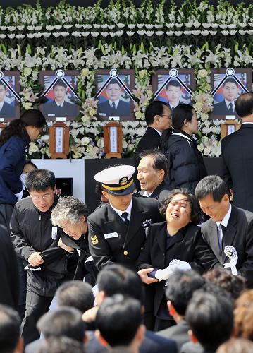 Family members of victims weep as they offer flowers to portraits of the deceased sailors from the sunken South Korean naval ship Cheonan during a funeral ceremony at a navy base at Pyeongtaek, south of Seoul Thursday, April 29, 2010. [Xinhua]