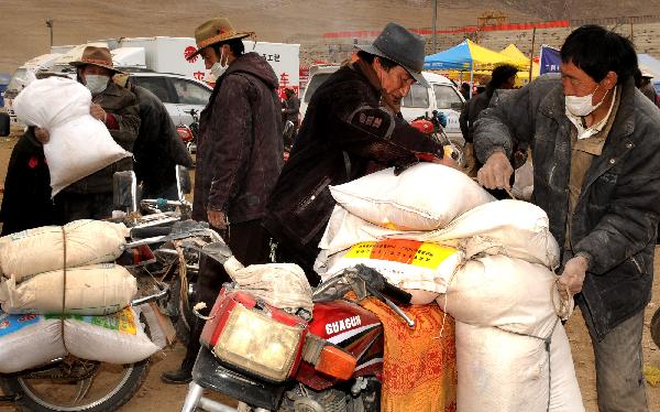 Local residents recieve flour and rice in Gyegu Town in quake-hit Yushu County, northwest China's Qinghai Province, April 28, 2010. Relief supplies were handed out to quake victims in Yushu. 