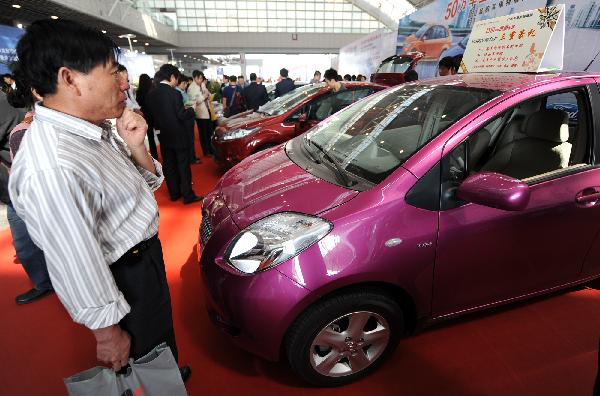 Visitors watch cars on display during the first day of an auto show in Nanjing, central China&apos;s Jiangsu Province, May 1, 2010. [Han Yuqing/Xinhua]