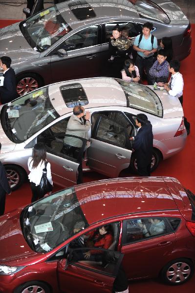 Visitors watch cars on display during the first day of an auto show in Nanjing, central China&apos;s Jiangsu Province, May 1, 2010. [Han Yuqing/Xinhua]