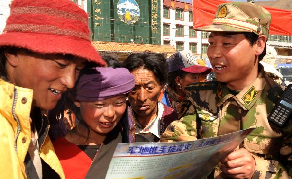 Yu Xiaoming (1st, R), member of the Xining detachment of the armed police force, explains quake-relief policies to local people in quake-hit Yushu County, northwest China&apos;s Qinghai Province, May 1, 2010. [Tao Ming/Xinhua]
