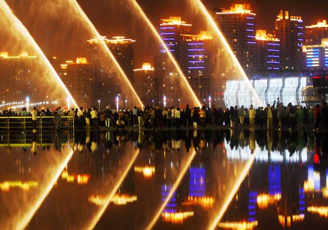 Visitors enjoy the night show of light and fountain in 2010 World Expo Site in Shanghai, China, May 2, 2010. The coordinating authority announced the plan of the light, fountain and music show in the Expo Site every hour from 19:00 every day, so as to attract more night visitors. [Xinhua]