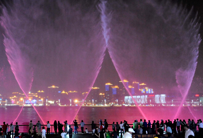 Visitors enjoy the performance of music fountain at the east bank of Huangpu River at the World Expo Park in Shanghai, east China, May 2, 2010. The night views of the World Expo Park with multicolored lights and various illumination effects give visitors different impression from the daytime. [Wang Song/Xinhua]