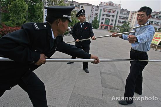 Security guards contain an attacker with specially designed forks in a mocked attack in Dongming Middle School in Weifang, East China's Shandong province May 2, 2010. In wake of a string of violent incidents against students, Chinese authorities are strengthening security checks and implementing measures to prevent assaults at schools and kindergartens. [Asianewsphoto]