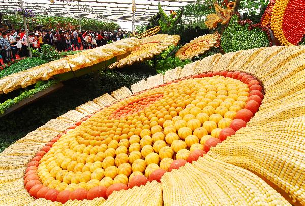 Visitors walk around to appreciate a unique breed of super long towel gourd, at the Vegetable Fair, which attracts great many visitors and procurators for sightseeing and deal-order by the virtue of new and high-tech cultivation methods, affluent varieties of strains, as well as novel horticultural sculpting, during the May 1 vacation, in Shouguang, east China's Shandong Province, May 2, 2010. The fair is slated to last until May 20. [Xinhua/Dong Naide]