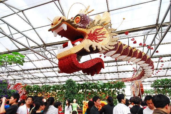 Visitors walk around beneath a unique super sculpting of China Dragon Soaring, at the Vegetable Fair, which attracts great many visitors and procurators for sightseeing and deal-order by the virtue of new and high-tech cultivation methods, affluent varieties of strains, as well as novel horticultural sculpting, during the May 1 vacation, in Shouguang, east China's Shandong Province, May 2, 2010. The fair is slated to last until May 20. (Xinhua/Dong Naide)