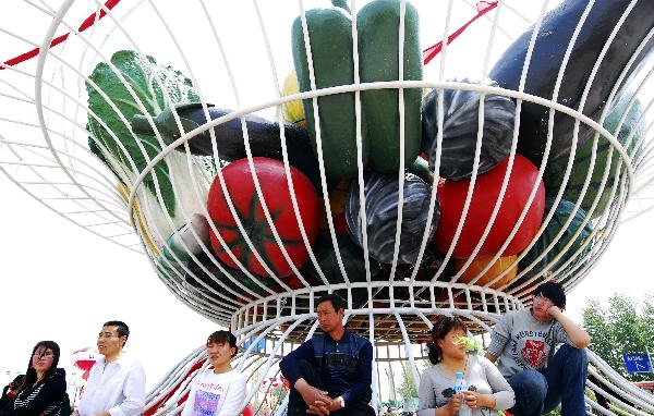 Several visitors take a recess beside a unique sculpting of vegetable basket, at the Vegetable Fair, which attracts great many visitors and procurators for sightseeing and deal-order by the virtue of new and high-tech cultivation methods, affluent varieties of strains, as well as novel horticultural sculpting, during the May 1 vacation, in Shouguang, east China's Shandong Province, May 2, 2010. The fair is slated to last until May 20. [Xinhua/Dong Naide]