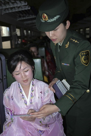A border policewoman returns a passport to a member of the Democratic People's Republic of Korea song and dance troupe in Dandong city, Liaoning province, May 2, 2010. The troupe and its 198 crew members will perform a Chinese classic, 'A Dream of the Red Chamber' in Beijing. The performance starts on May 6 and ends May 9.