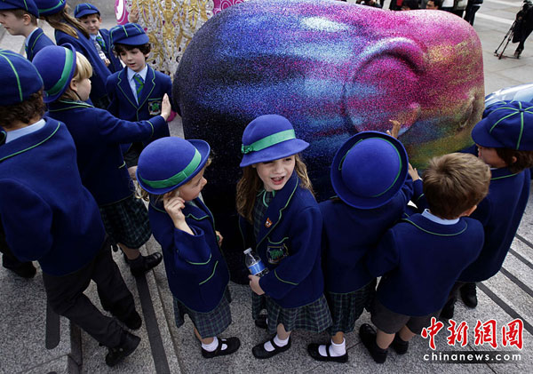 School children look and touch an elephant artwork in Trafalgar Square in London, May 4, 2010. The London Elephant Parade 2010 will see the capital taken over by 260 life-size baby elephants, all hand-painted by an assortment of established and emerging talent from the art and design world.[chinanews.com.cn]